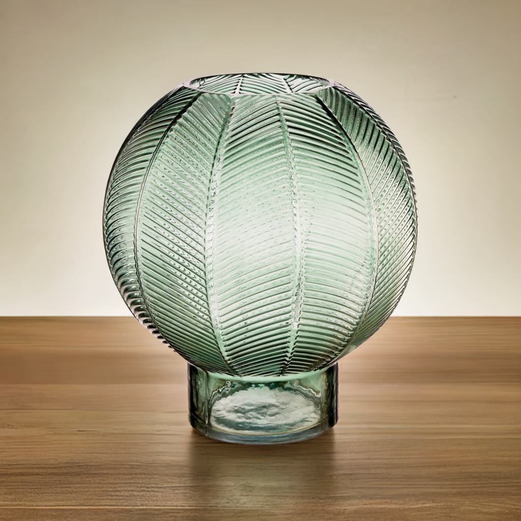 A spherical, art deco style green glass vase with ridged patterns around it